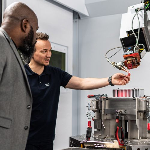 TRUMPF Mitarbeiter zeigt Kunden den Laserkopf eines Lasersystems