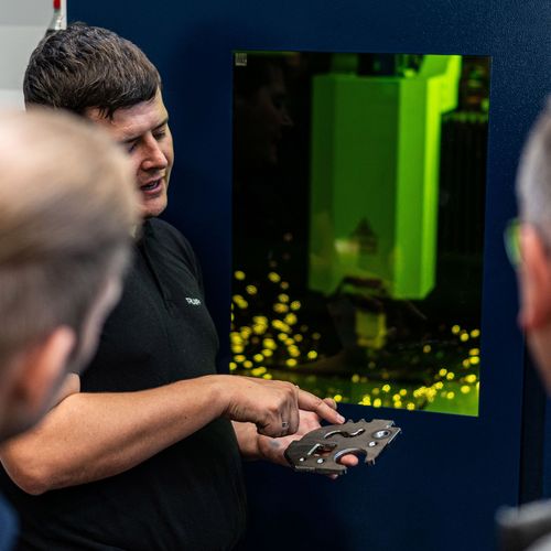 TRUMPF Mitarbeiter zeigt Kunden ein Blechteil