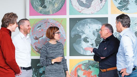 TRUMPF employees talking in front of part of a painting 